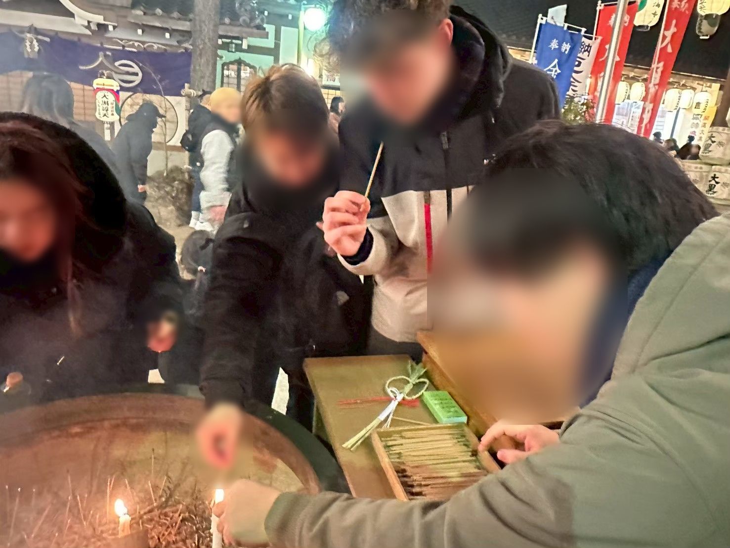 ろうそくに火を灯して初詣をする住人たち