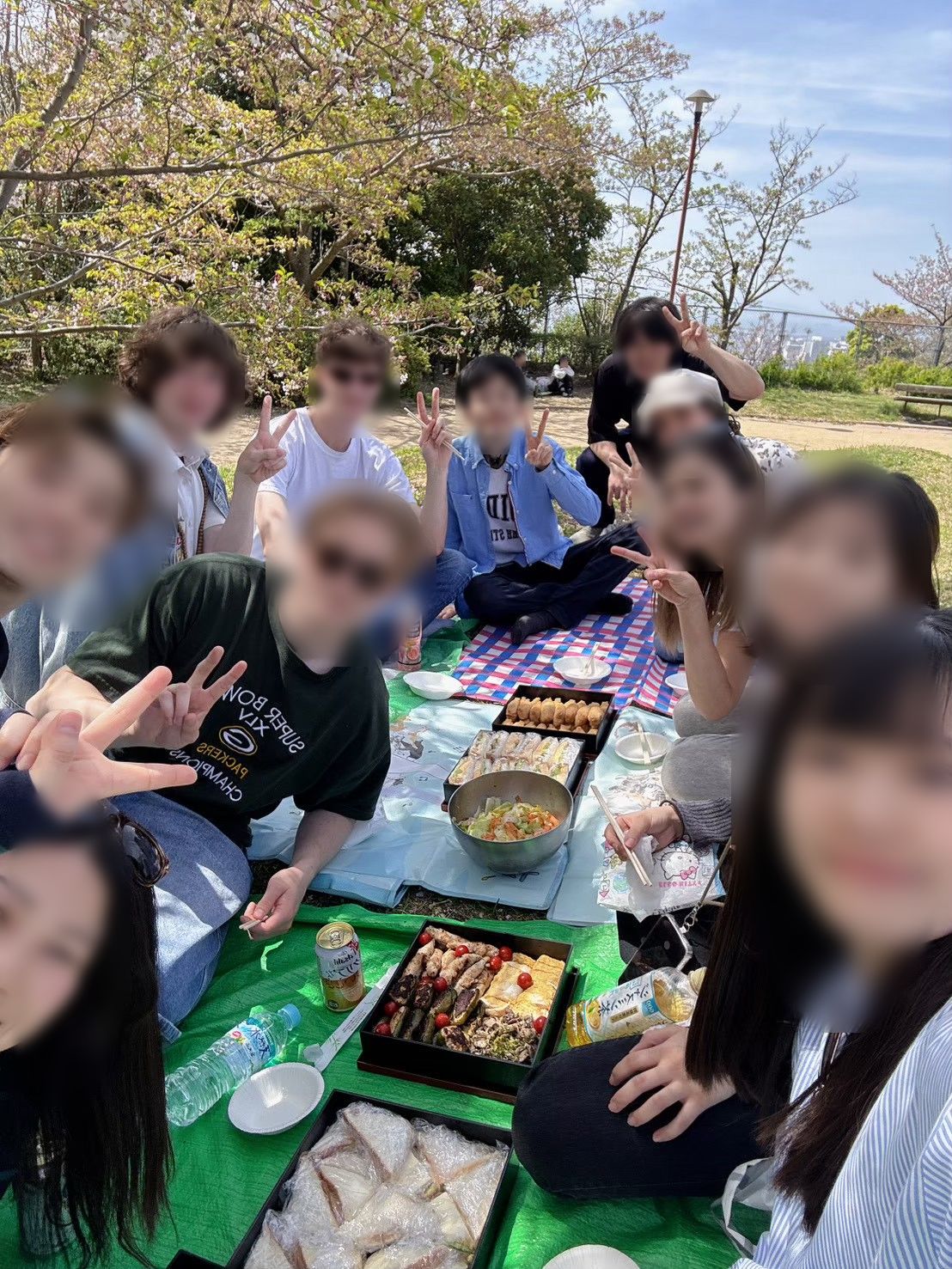 桜をバックに集合写真。ピースサインをする住人と友達