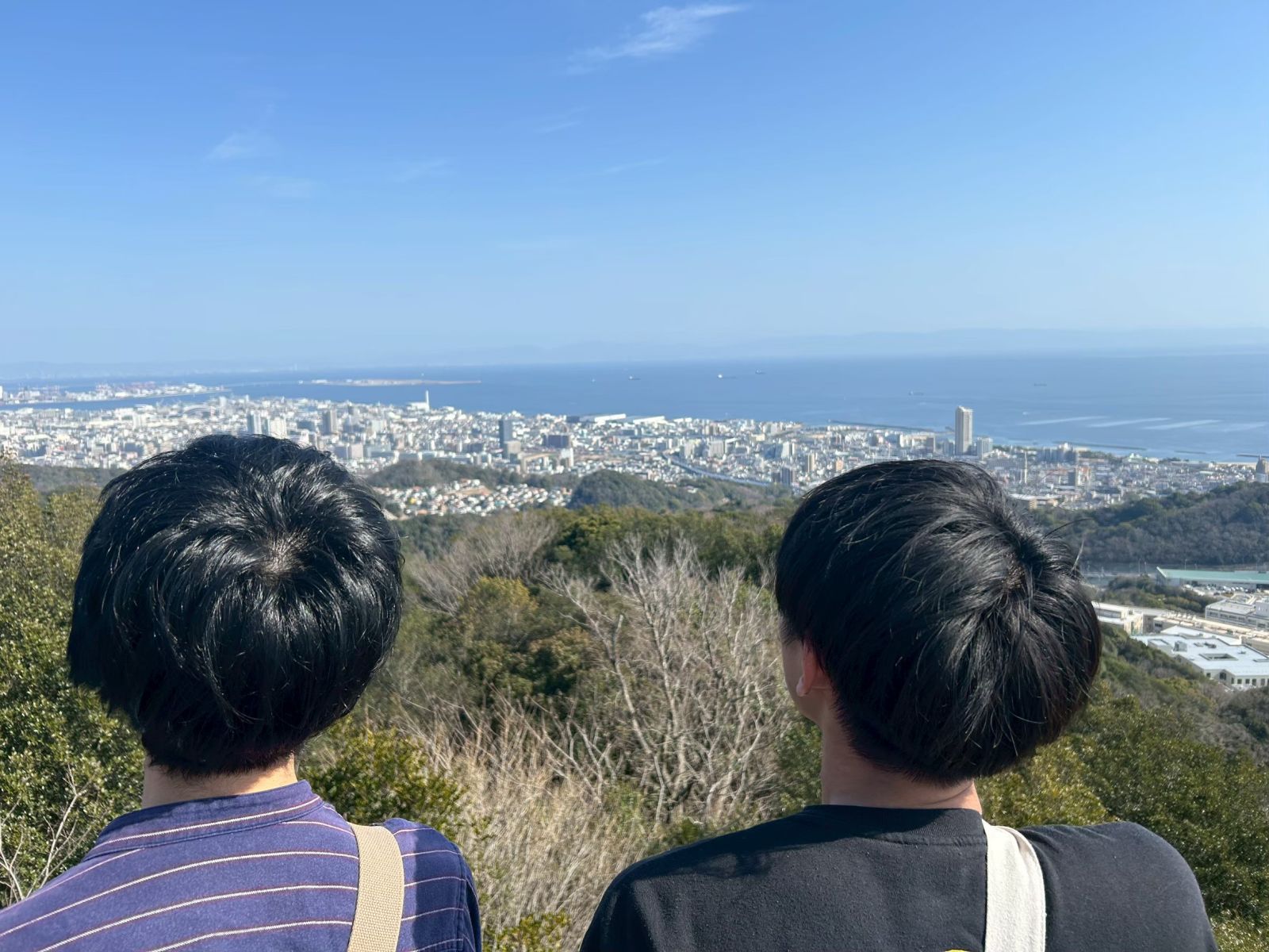 山頂から神戸の街と海を眺めるふたり